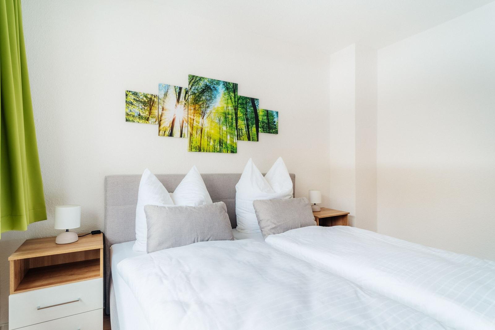 Schlafzimmer mit Bett, Nachttischen und Wandbildern