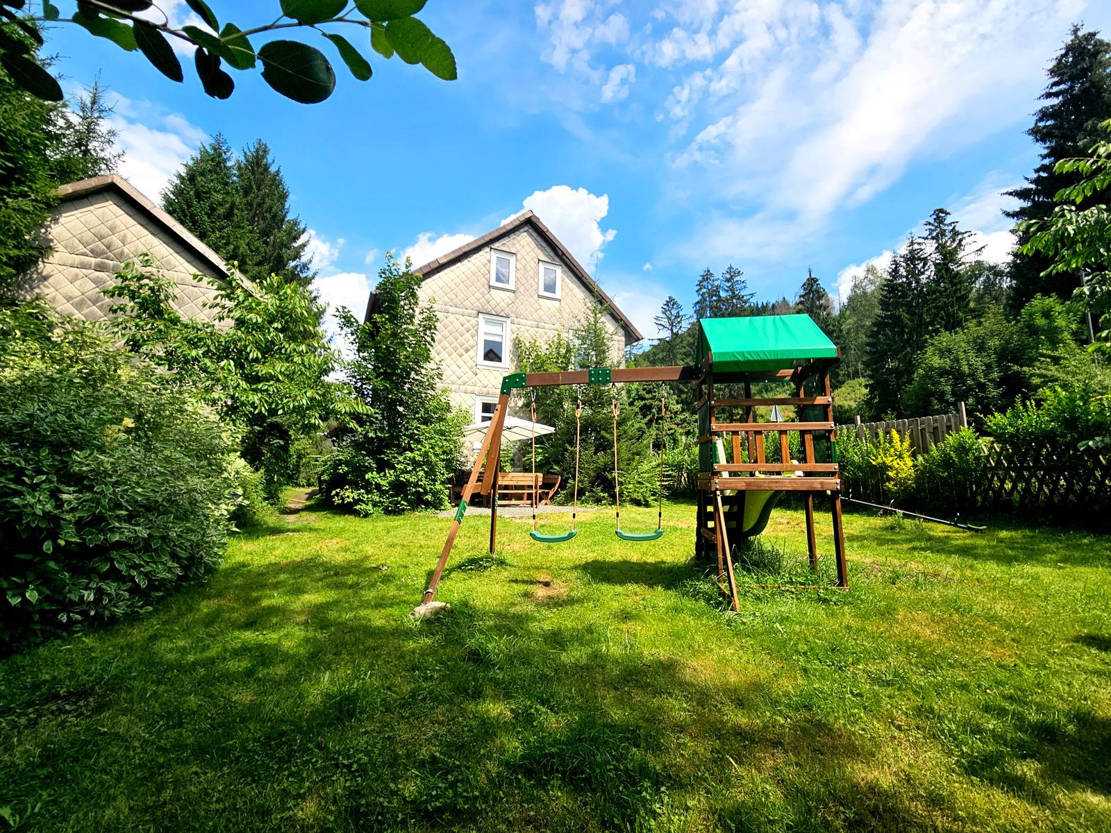 Garten links vom Haus ist mit Spielplatz und Terrasse