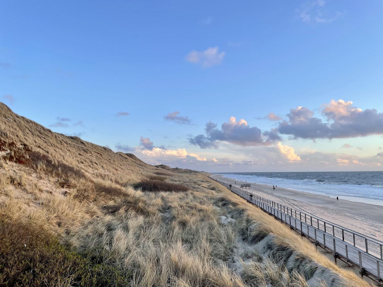 Wellen brechen auf dem Strand. Horizont mit blauem Himmel und weißen Wolken.