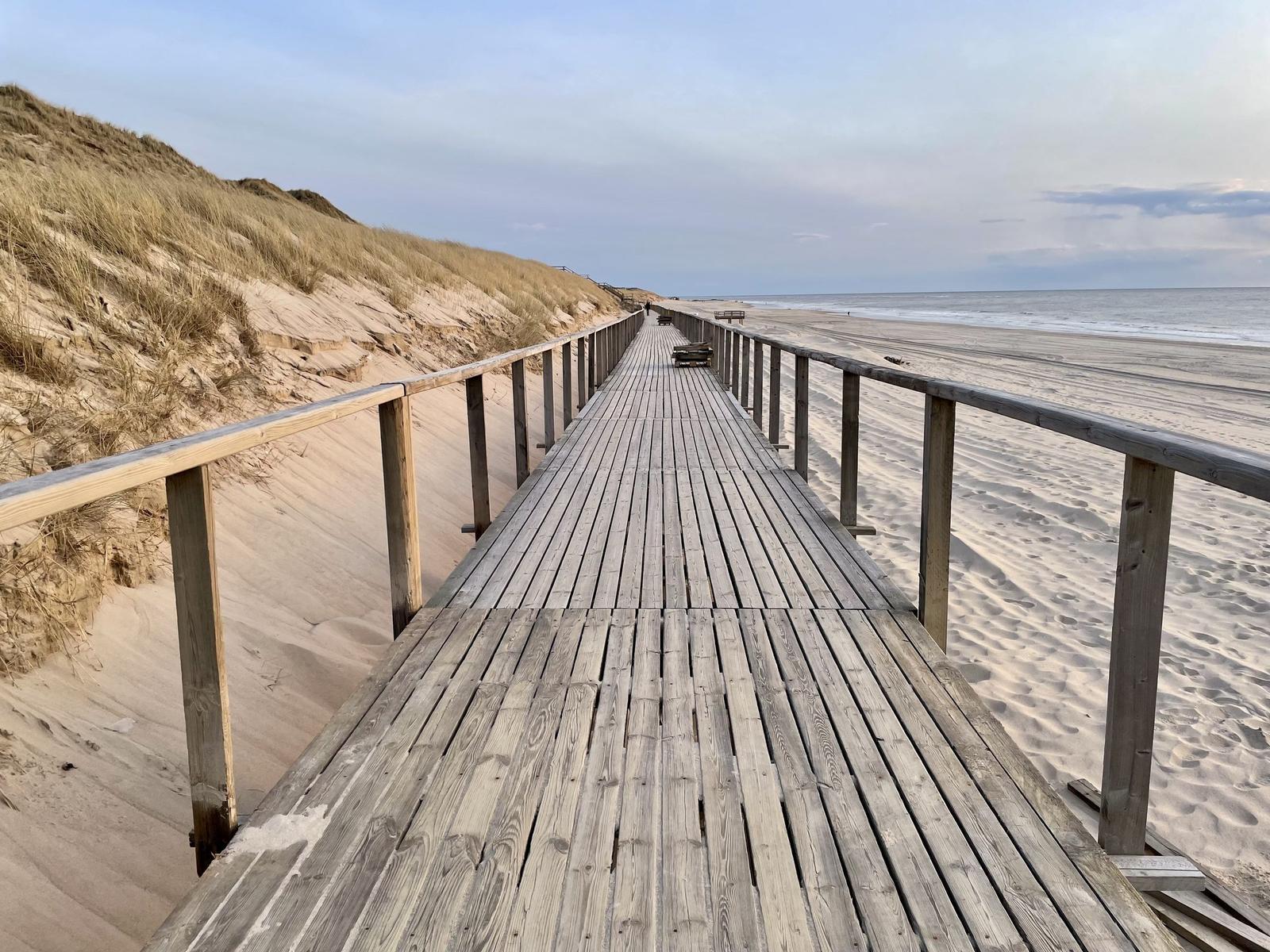 Beach chairs with blue-white stripes stand on sand.