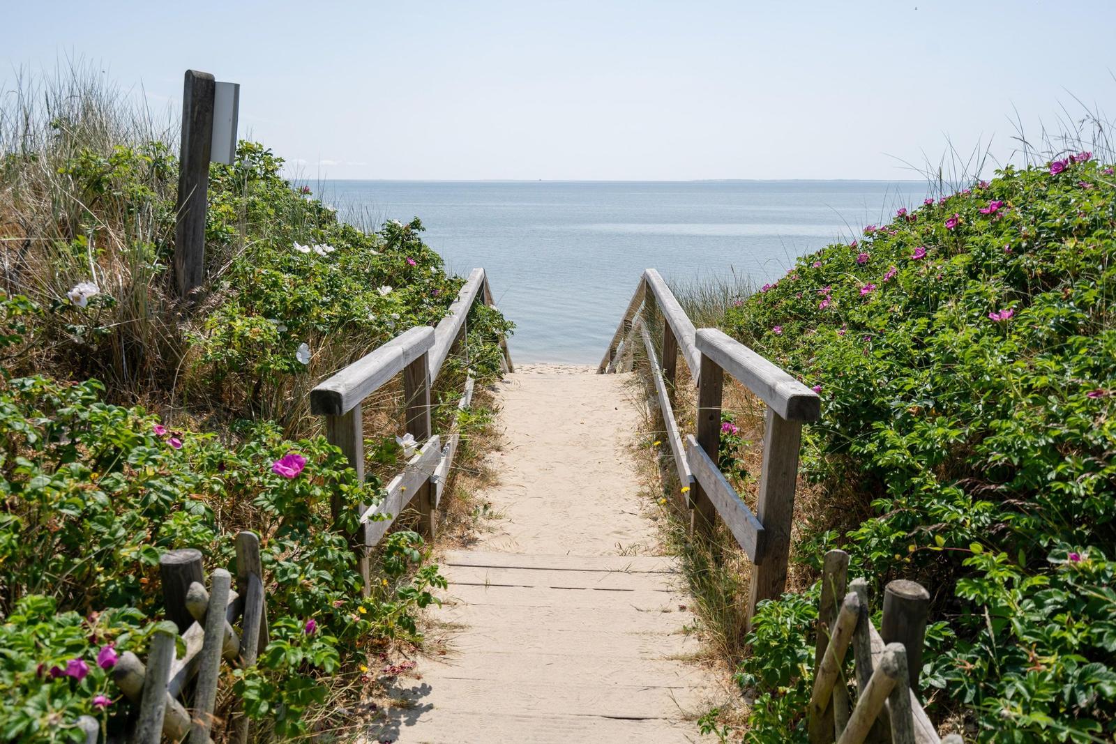 Strand mit Sandkästen und Dünen. Im Hintergrund ein Mehrfamilienhaus.