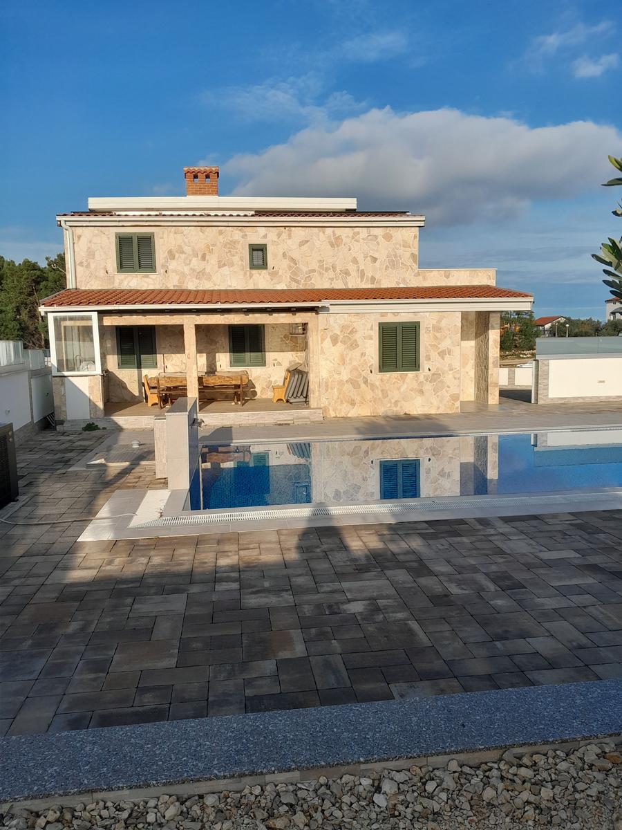 Haus mit Pool und Terrasse unter blauem Himmel