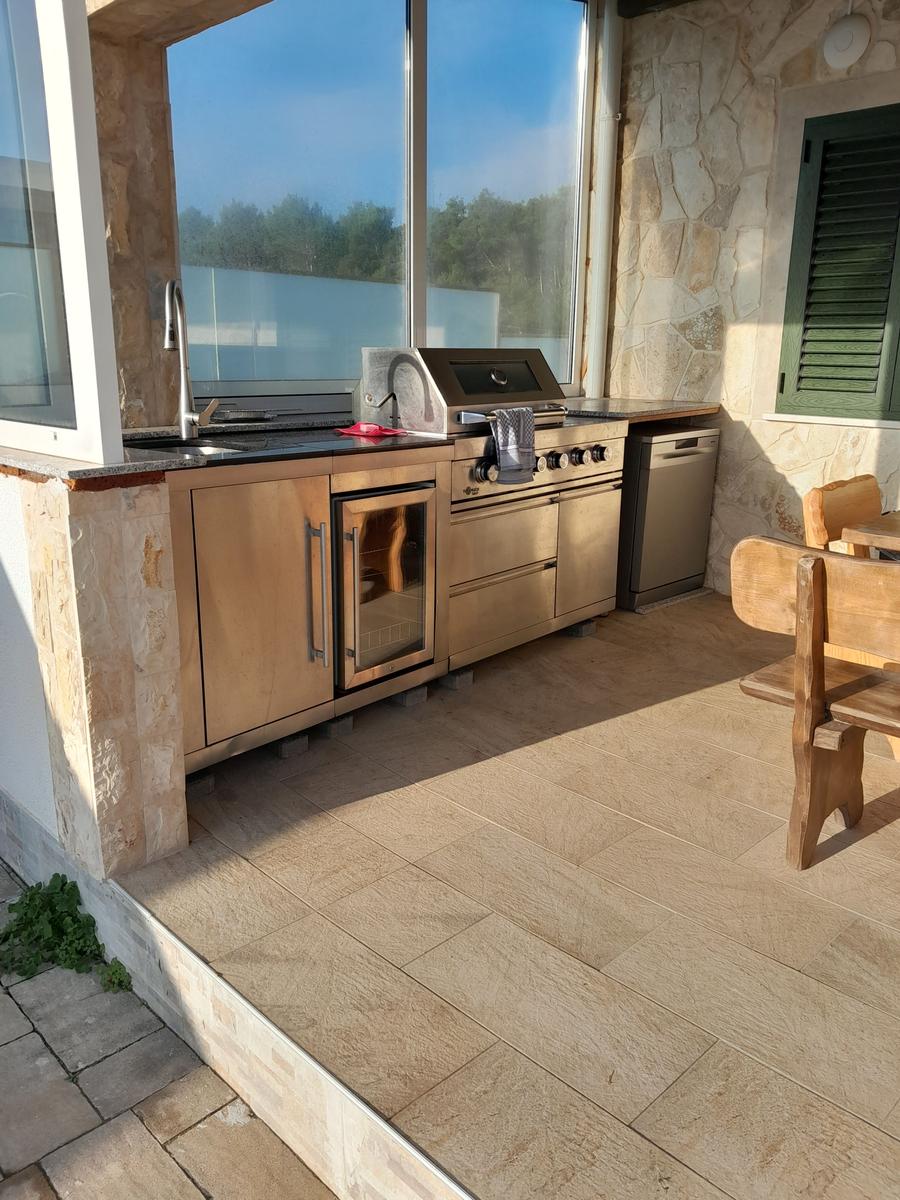 Außenküche mit Grill, Spüle und Waschmaschine an Steinwand