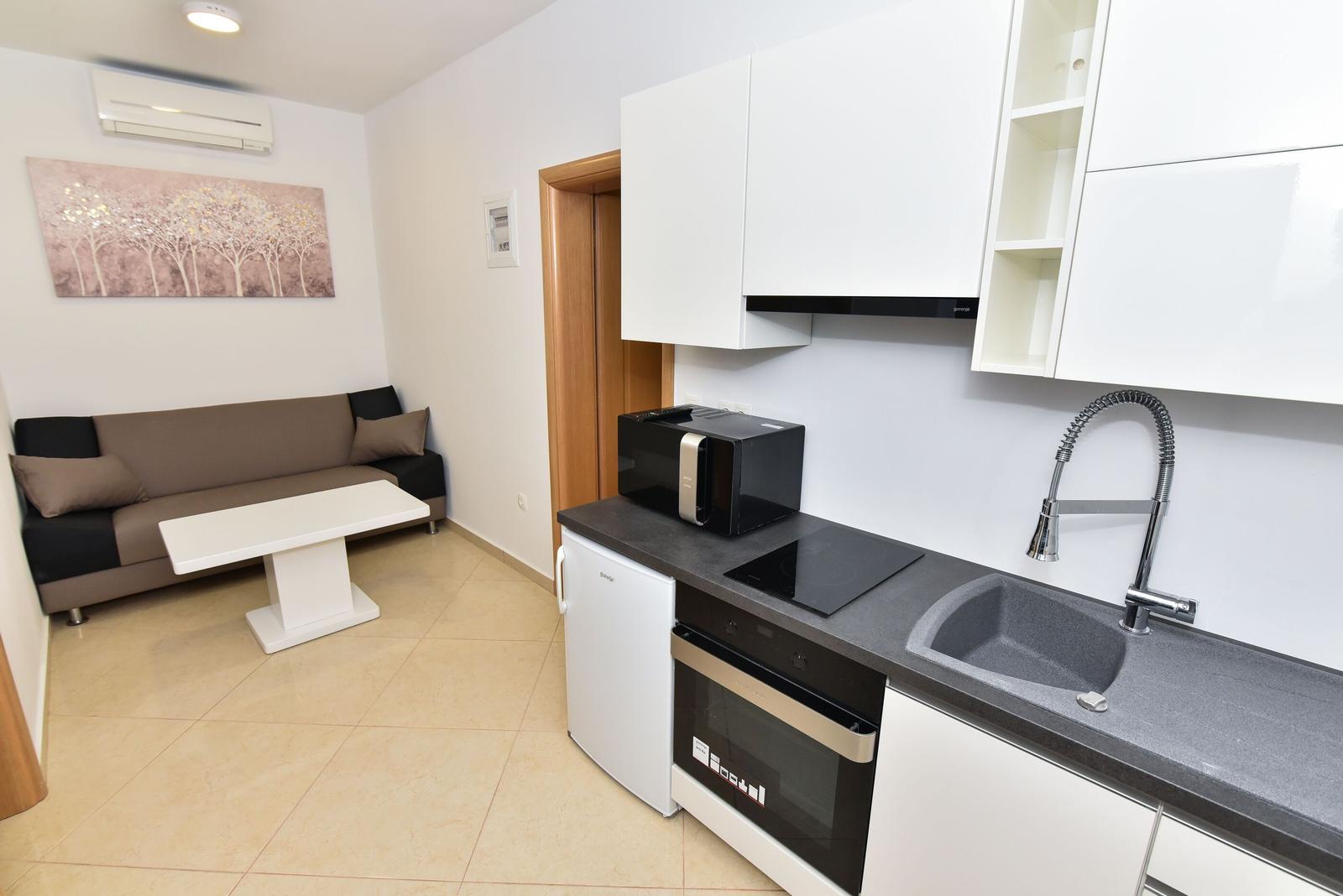 Küche mit Spüle, Herd und Kühlschrank. Wohnbereich mit Sofa und Tisch.