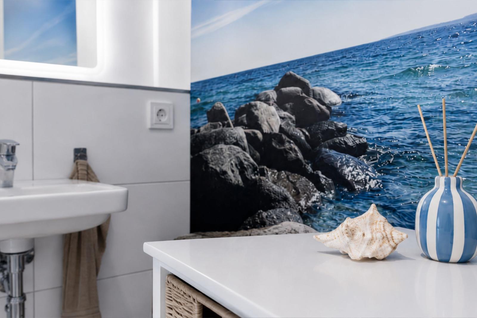 Badezimmer mit Meeresmotiv an der Wand, Waschbecken und Schale auf Schrank