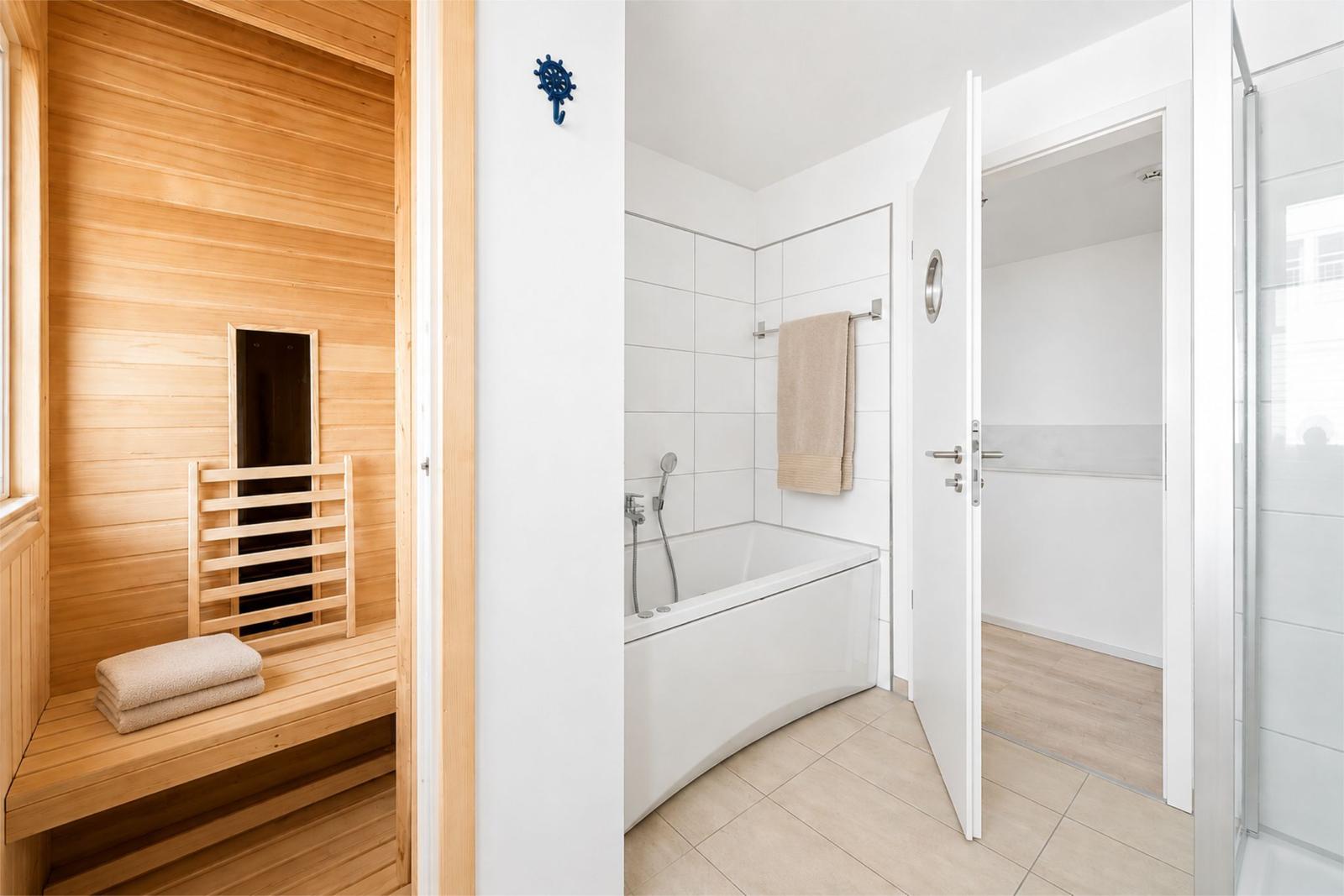Sauna mit Holzbank und Dusche mit Badewanne