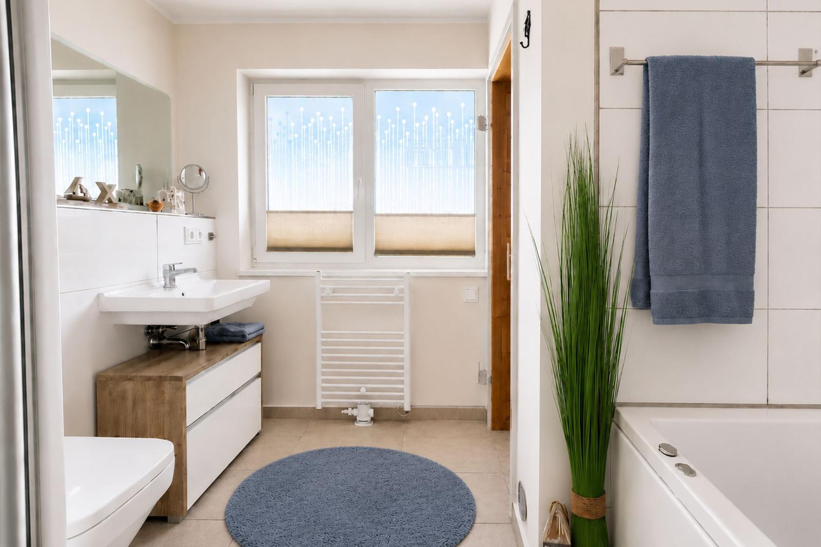 Badezimmer mit Badewanne, Waschbecken und Fenster mit Blick.