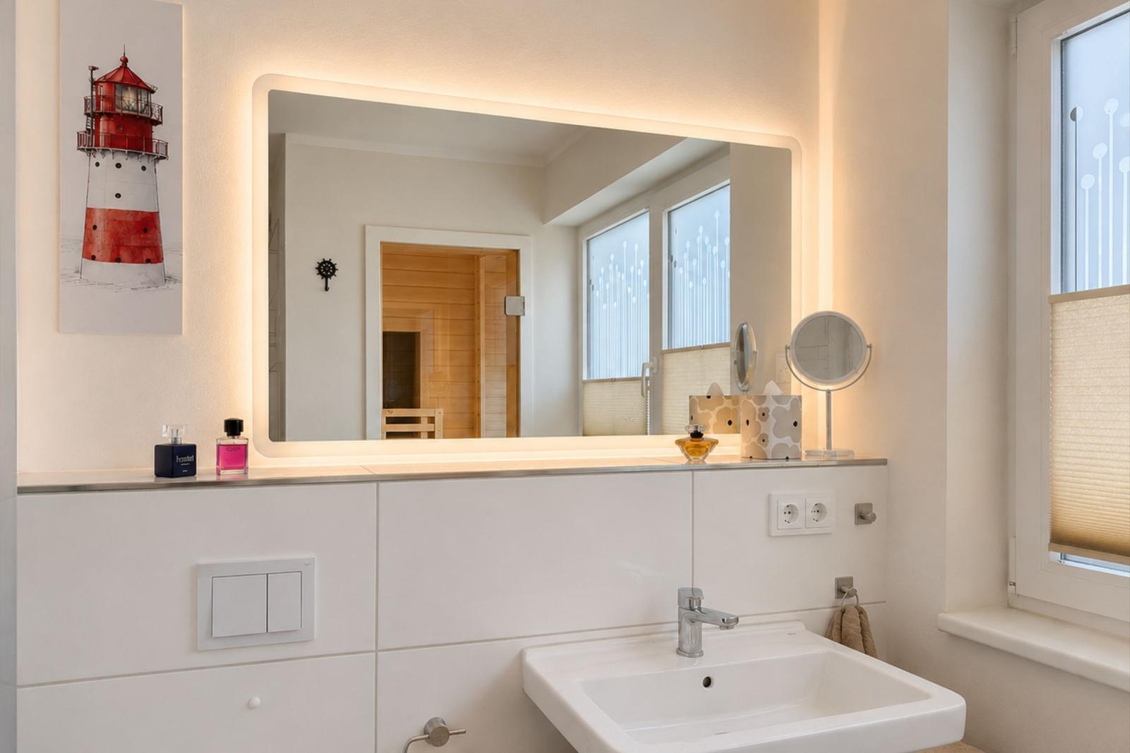 Badezimmer mit beleuchtetem Spiegel, Waschbecken und Fenster.