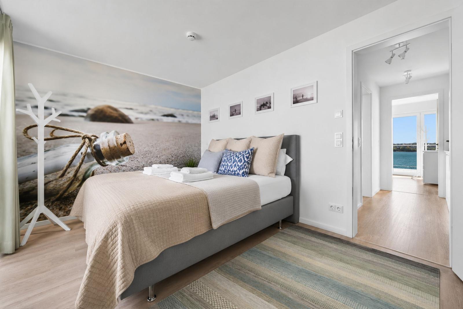 Schlafzimmer mit Bett, Wandbild und Blick aufs Meer