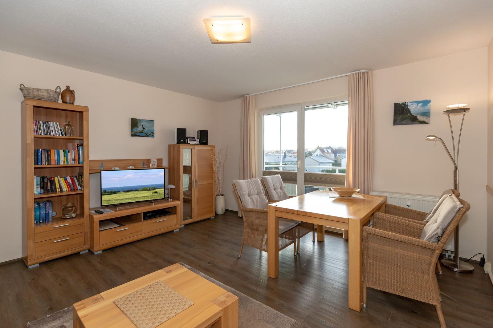 Living and dining area with wooden furniture, TV, and balcony view.