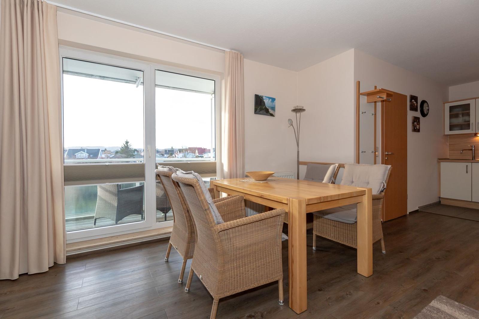 Dining room with wooden table, wicker chairs, and view of balcony.