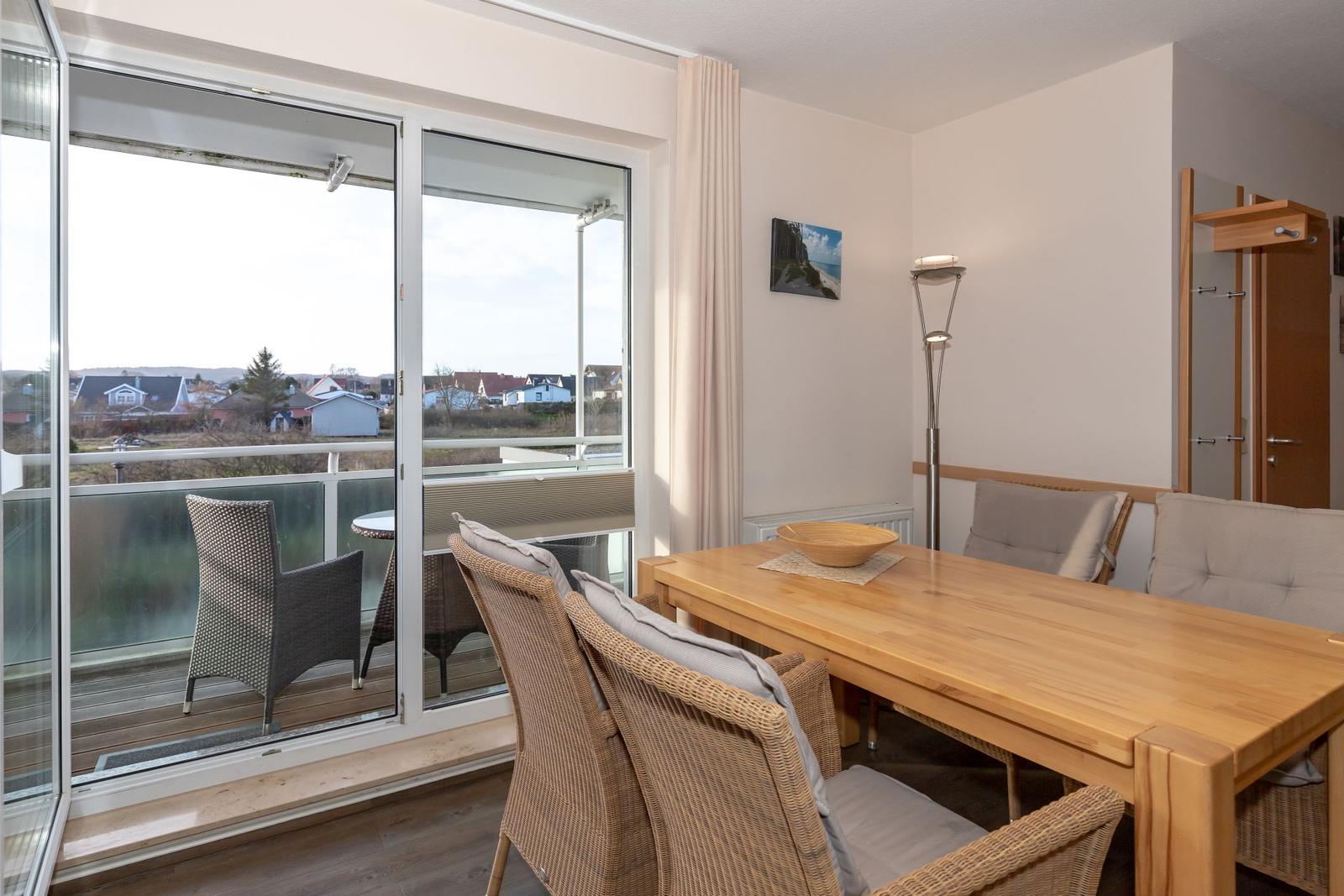 Dining room with wooden table, chairs, and balcony view
