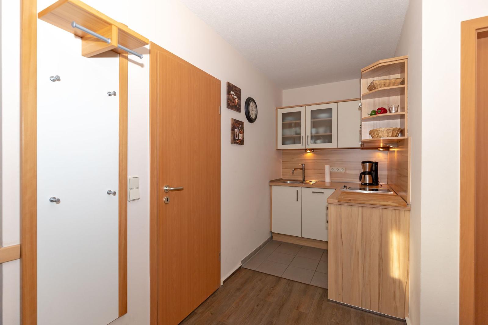 Kitchen with wooden cabinets, sink, coffee machine, and open shelves.