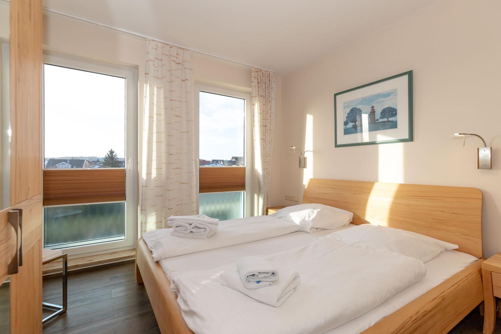 A bedroom with a wooden bed, windows, and a picture on the wall.