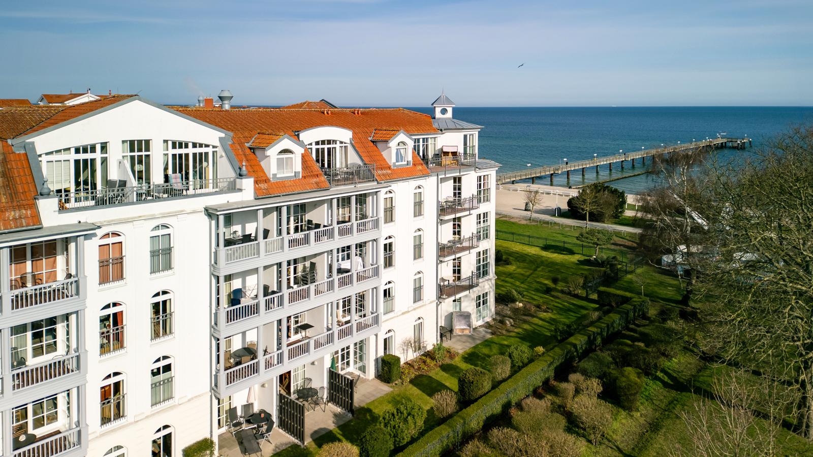 Wohnhaus mit Balkonen und Terrassen, Blick auf Meer und Pier.
