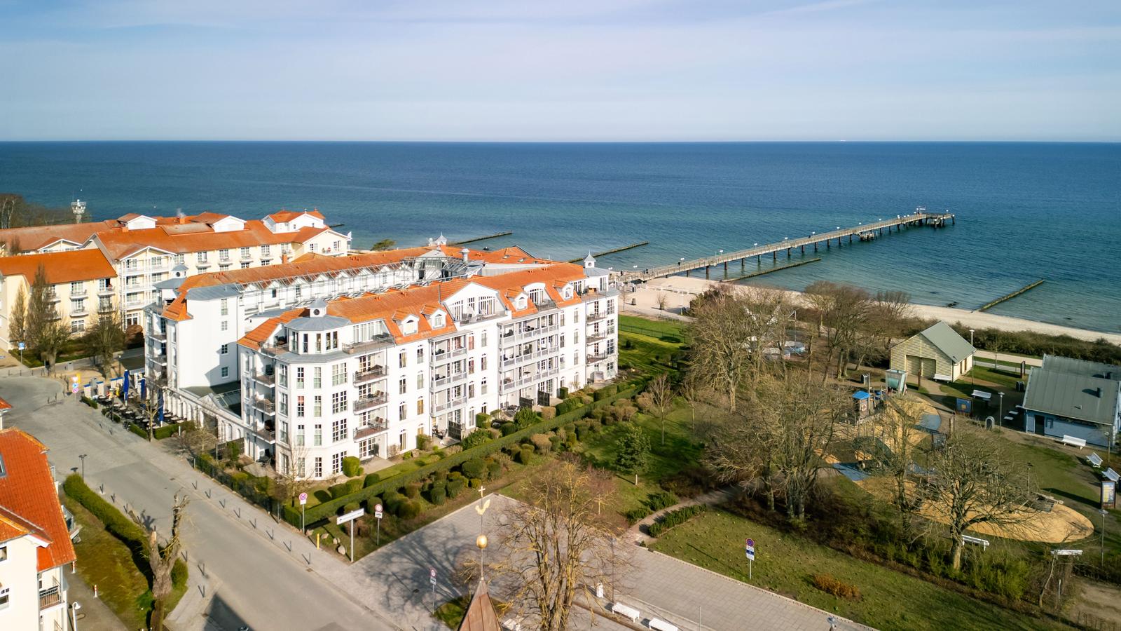 Meerfrontlage mit Hotel und Steg. Grünanlagen und Parkplätze.