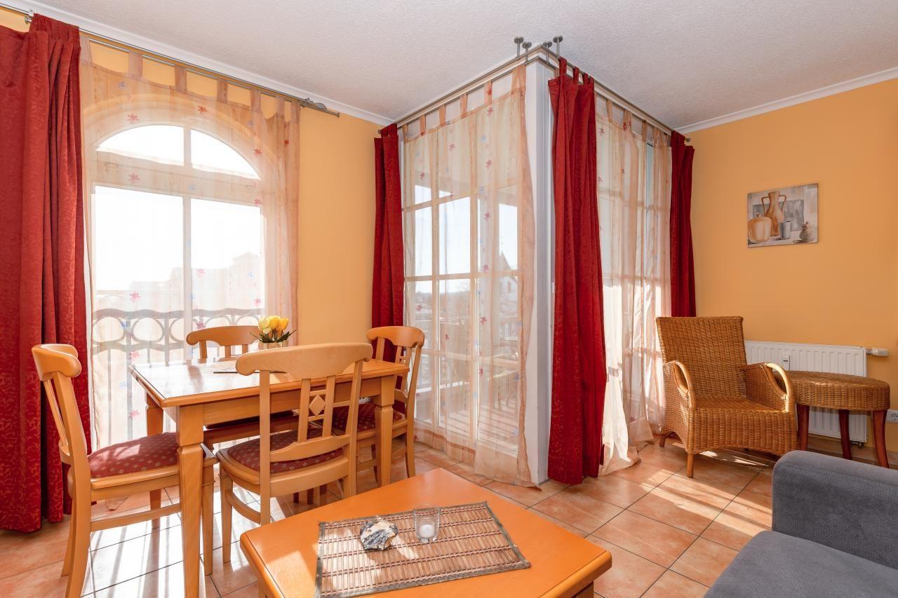 Esszimmer mit Tisch, Stühlen und Blick auf Balkon. Wohnbereich mit Sessel und Couch.