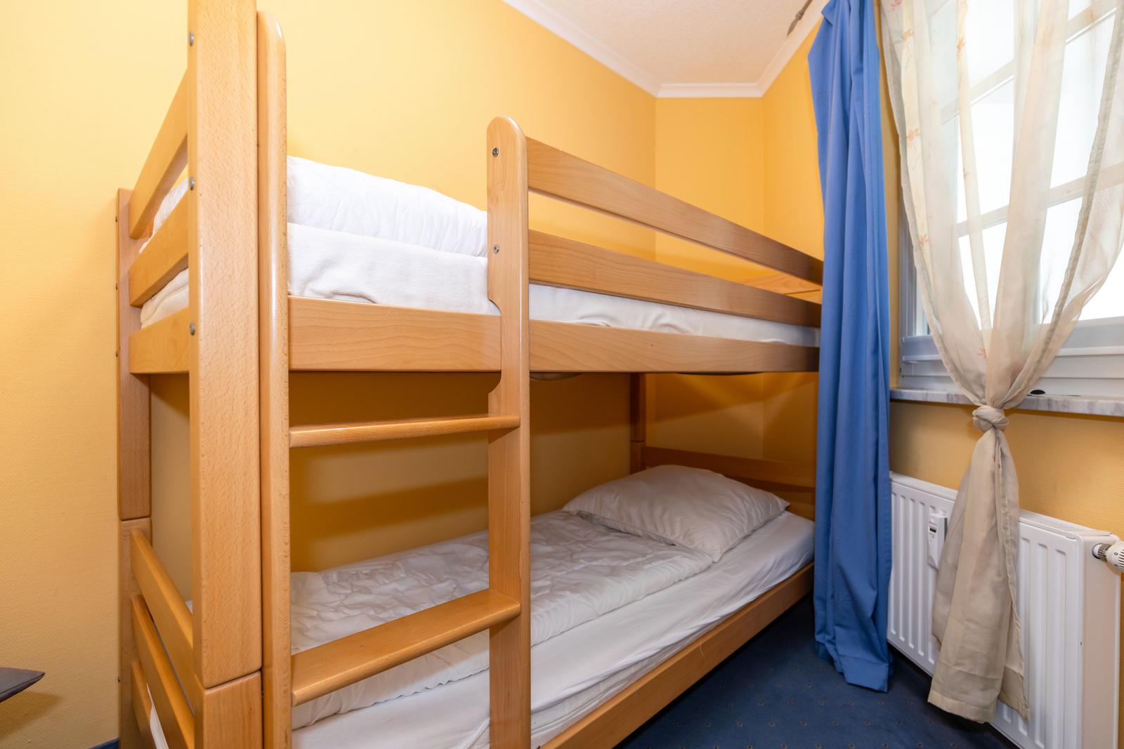 Ein Schlafzimmer mit einem Holzbett und einem Fenster mit Vorhängen.