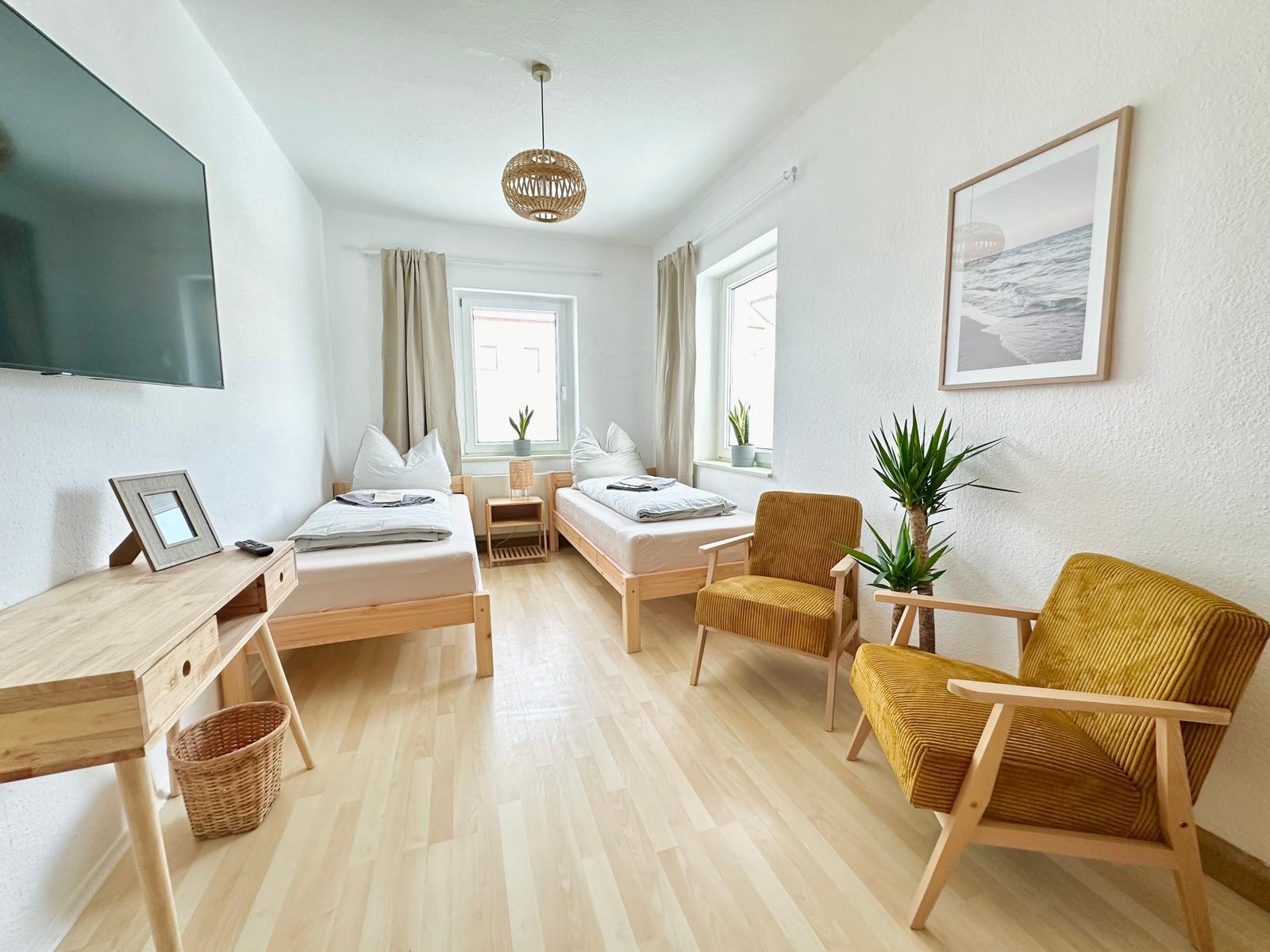 Schlafzimmer 1 mit zwei Einzelbetten (90 x 200 cm), 2 Sessel, Schreibtisch und schwenkbarem 55“ TV