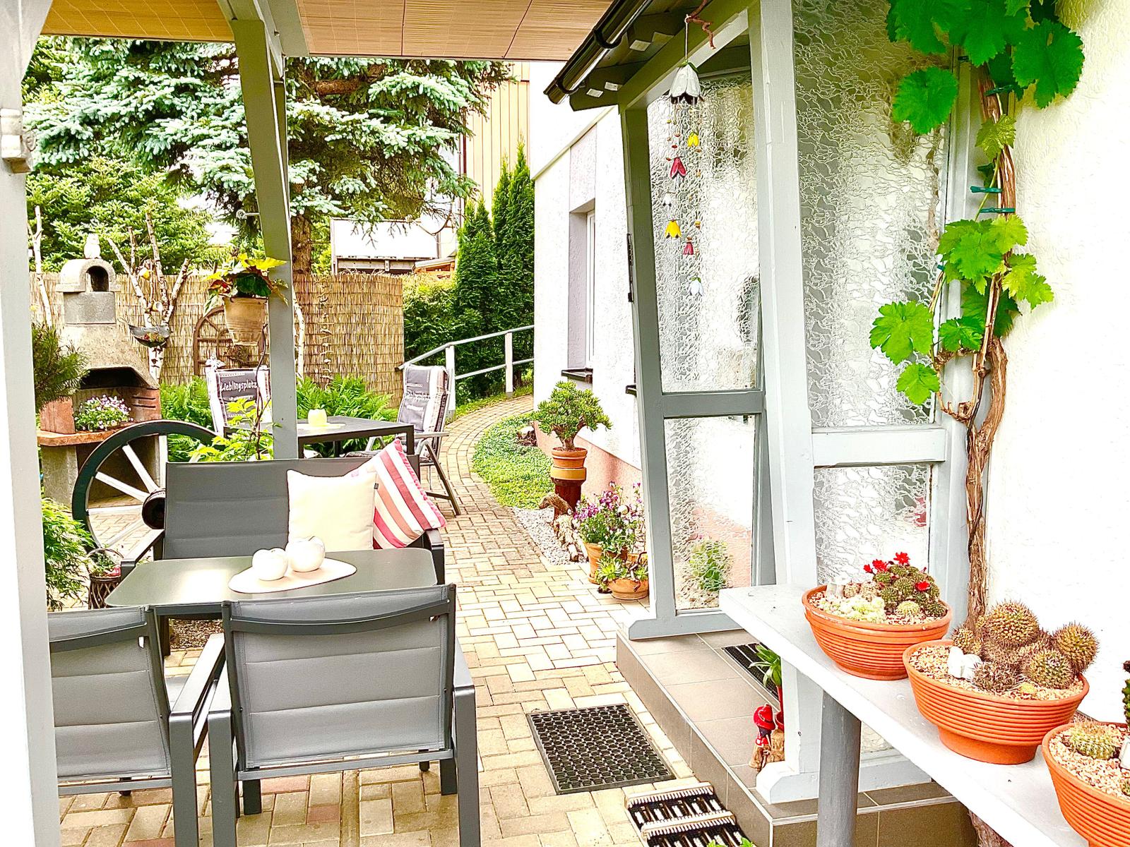 Terrasse mit Sitzgruppe, Pflanzen und Gartenterrasse. Durchgang zur Küche.