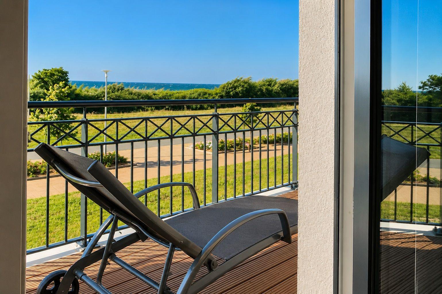 Terrasse mit Liegestuhl und Blick auf Strand und Grünfläche