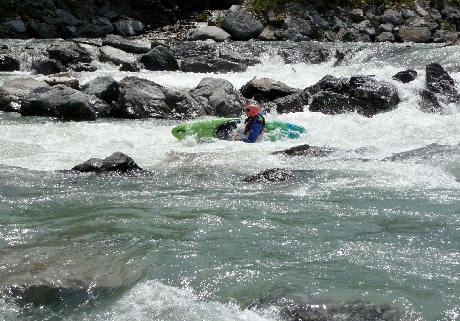 Ein Kajakfahrer navigiert durch einen steinigen Fluss.