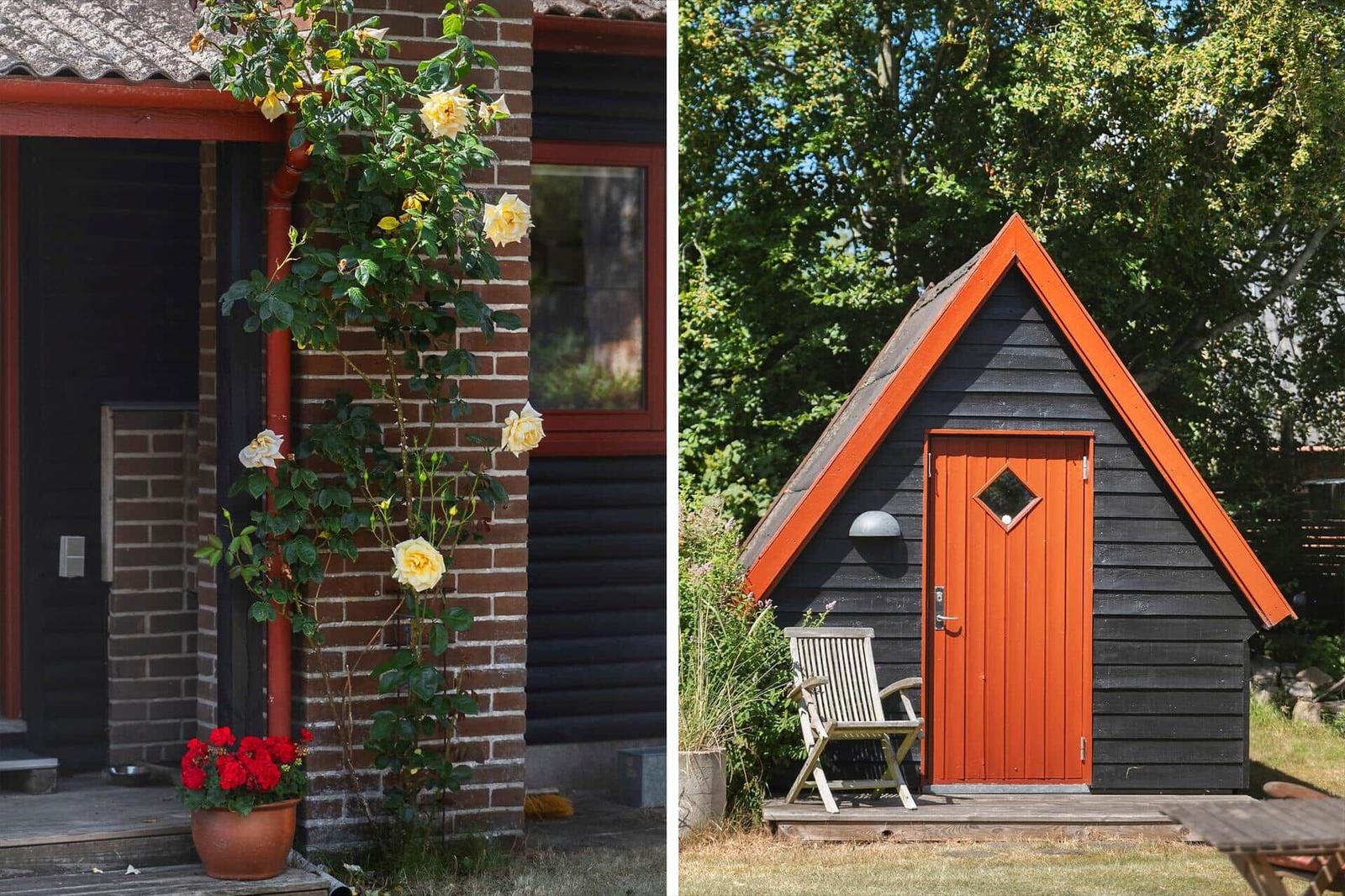 Außenbereich mit Tisch, zwei Stühlen und Sonnenschirm vor einem Holzhaus mit Blumen.