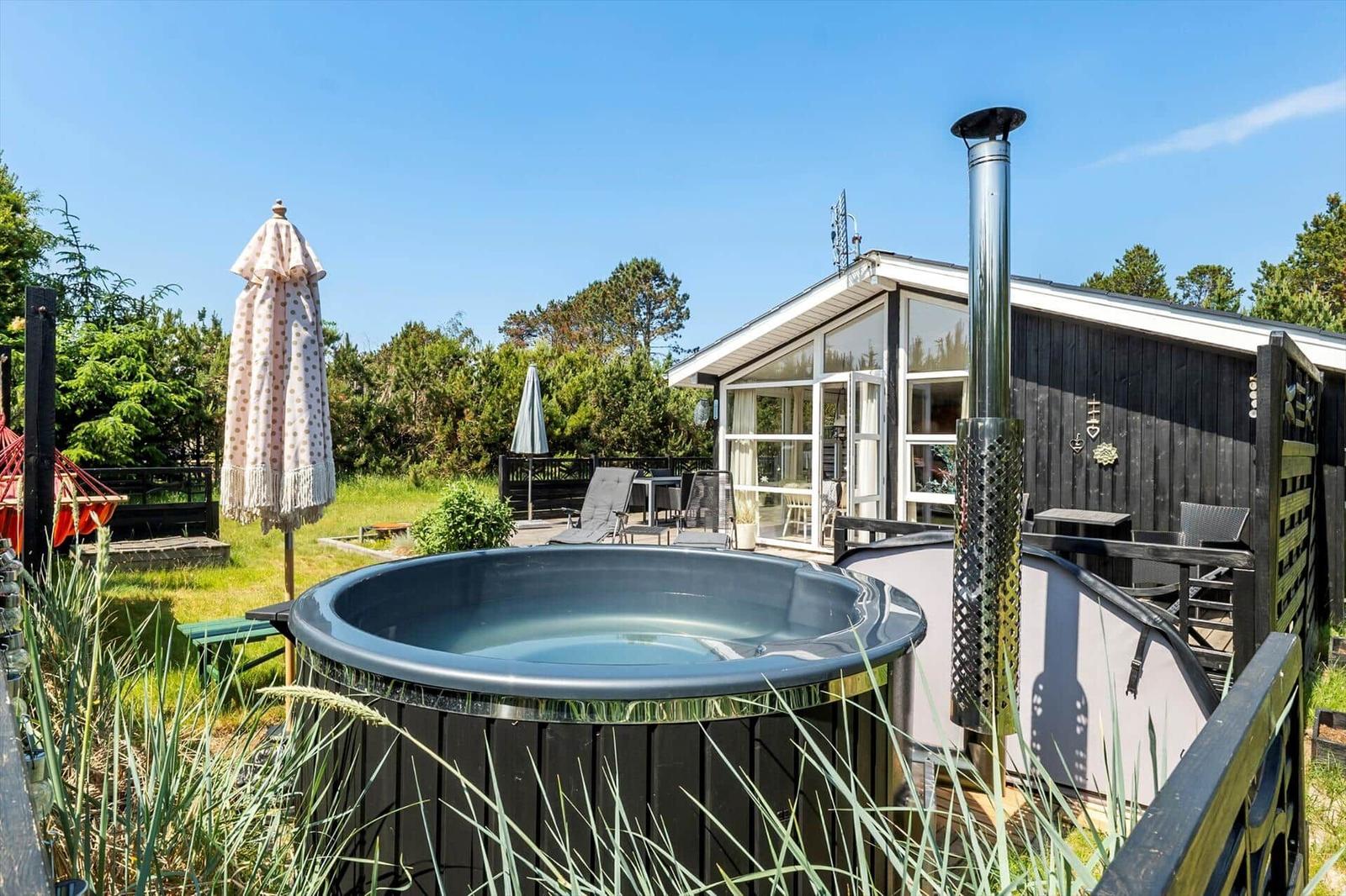 Haus mit Terrasse, Liegen, Whirlpool und rotem Hängemattenbereich.