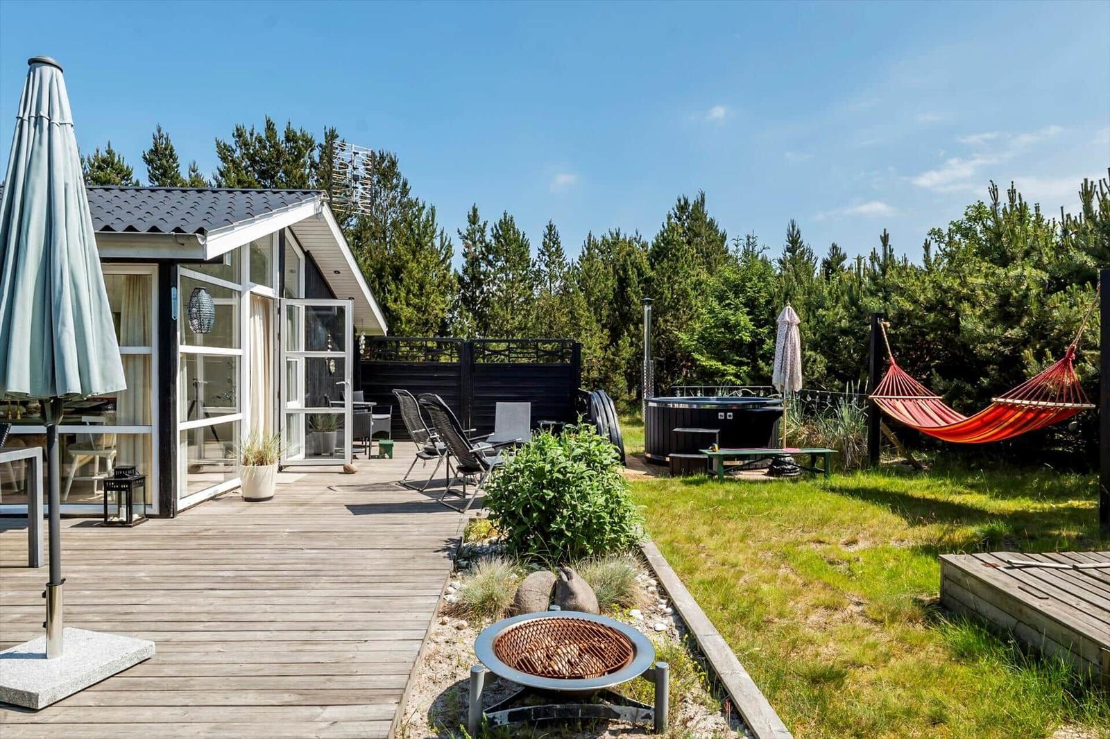 Esszimmer mit Tisch, Stühlen und Spielplatte. Große Fenster und Holzboden.