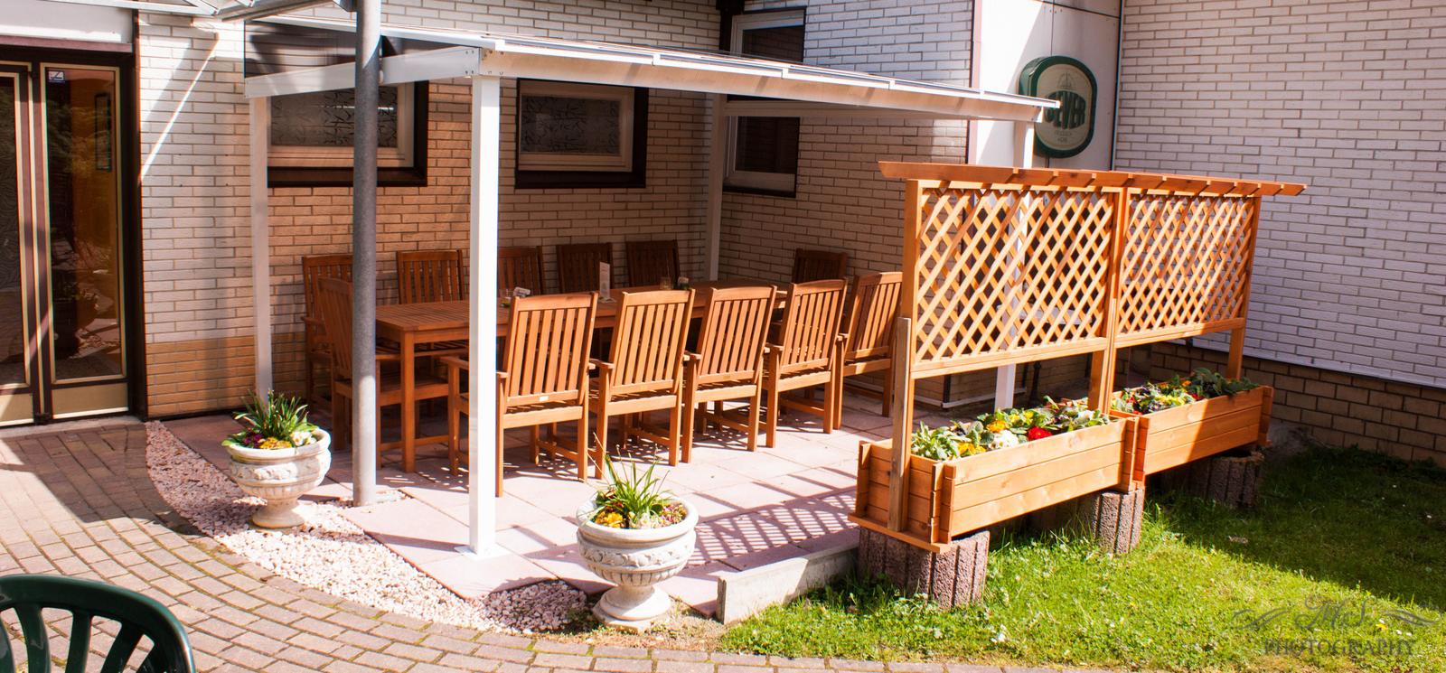 Terrasse mit Tisch, Stühlen und Blumenkästen unter Dach