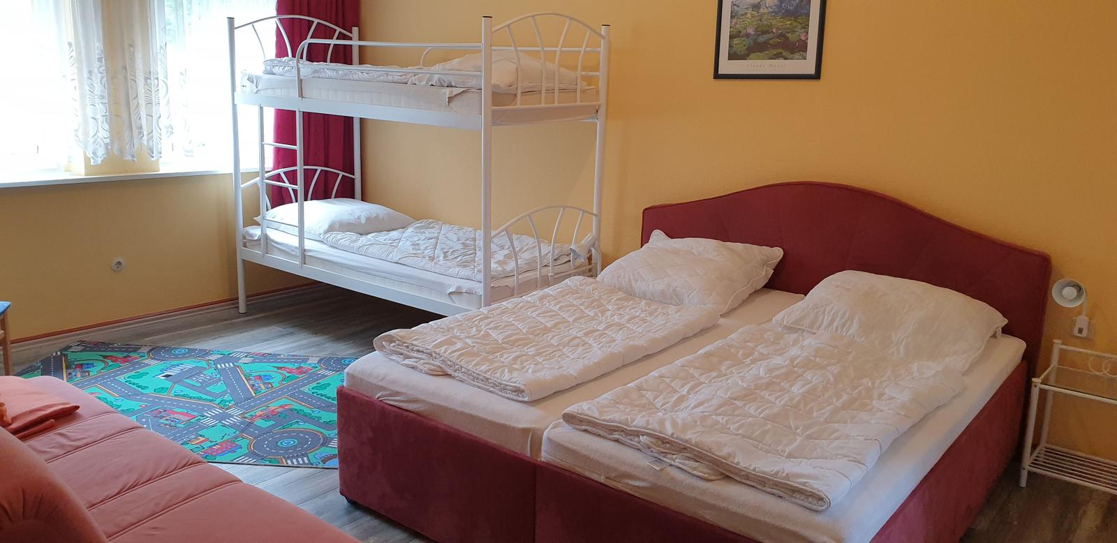 Zimmer mit Doppelbett, Schlafcouch und Klettertreppe. Wandfarbe gelb, Teppich mit Straßendesign.