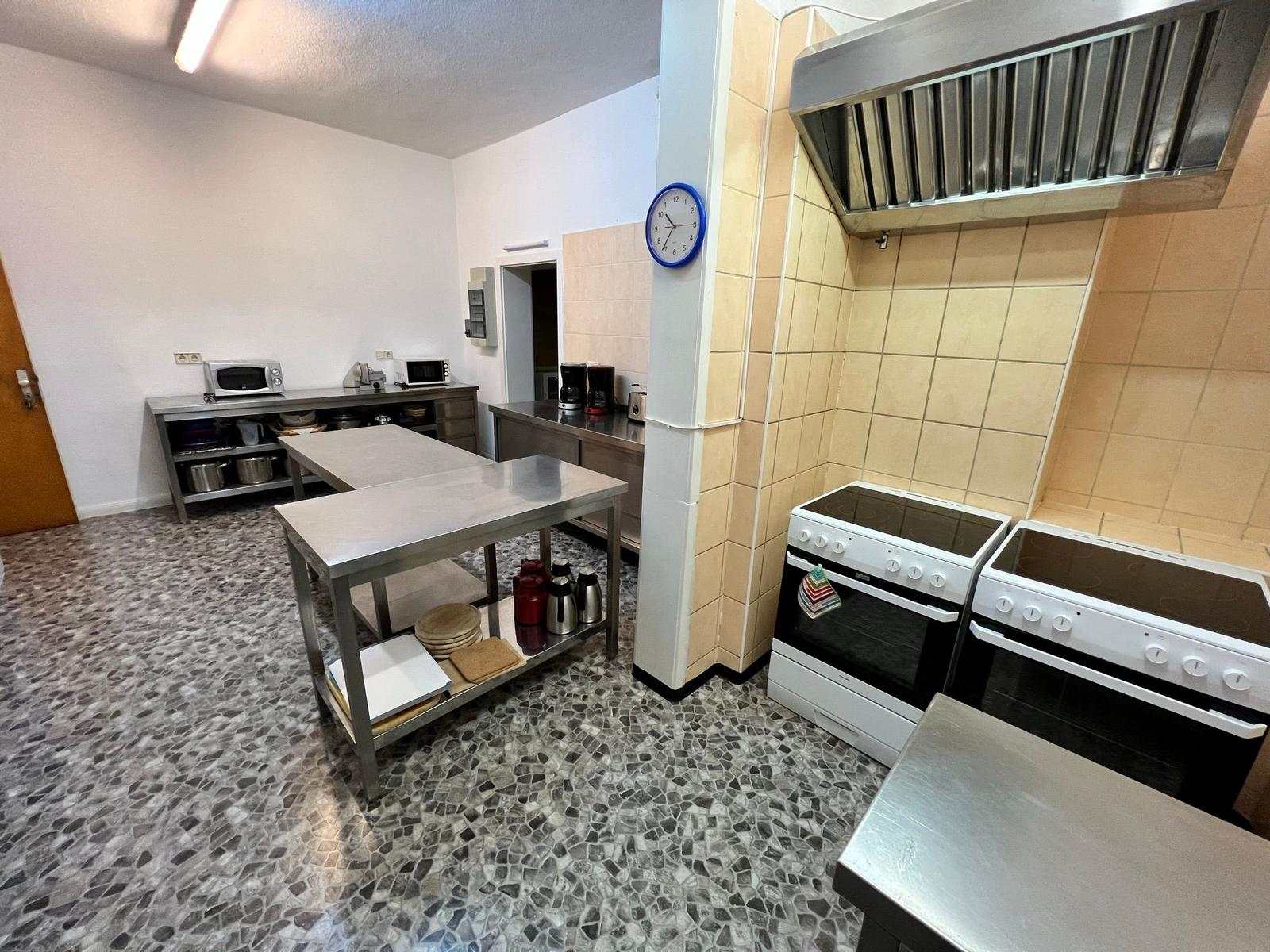 Küche mit Edelstahlarbeitsplatten, zwei Herden und Mosaikboden.
