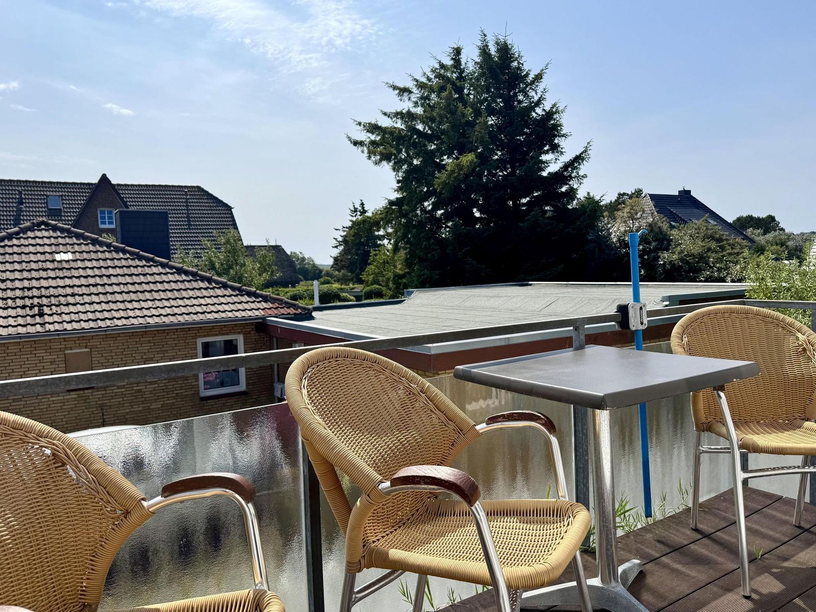 Balcony with wicker chairs, small table, wooden deck and glass railing