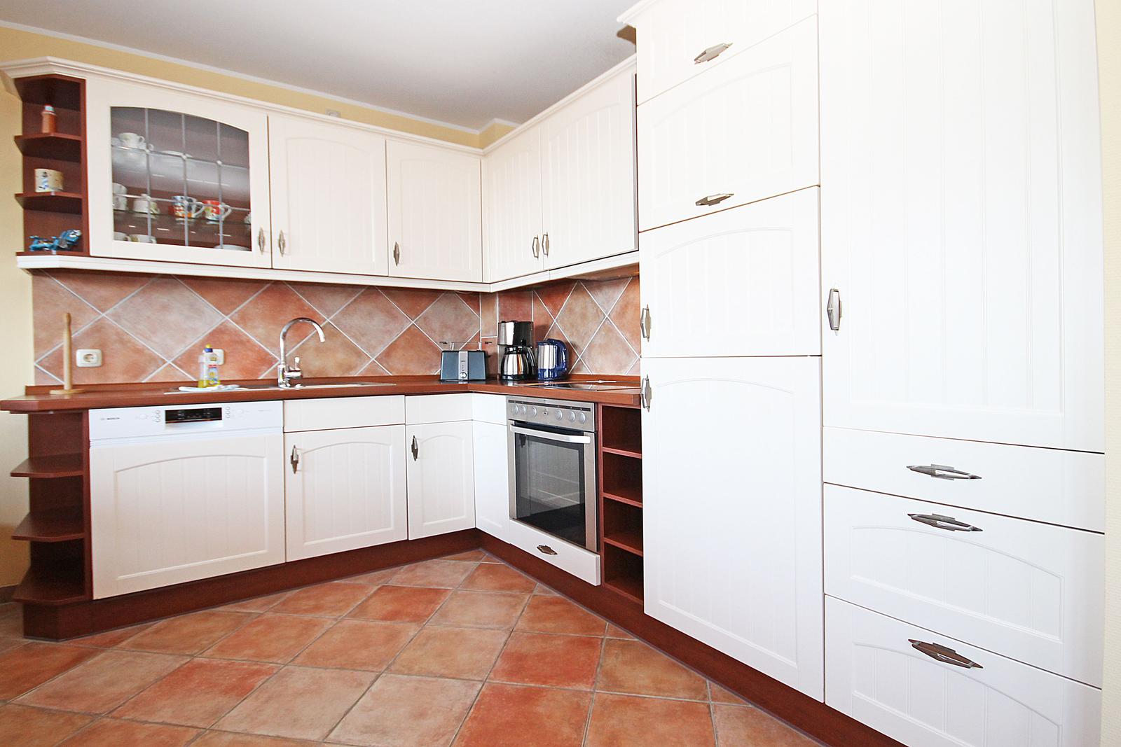 Küche mit weißen Schränken, braunem Arbeitsplatz und Backofen.
