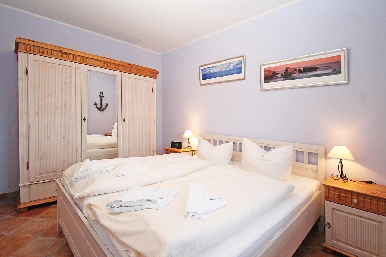 Schlafzimmer mit Doppelbett, Kleiderschrank und Nachttischen mit Lampen.