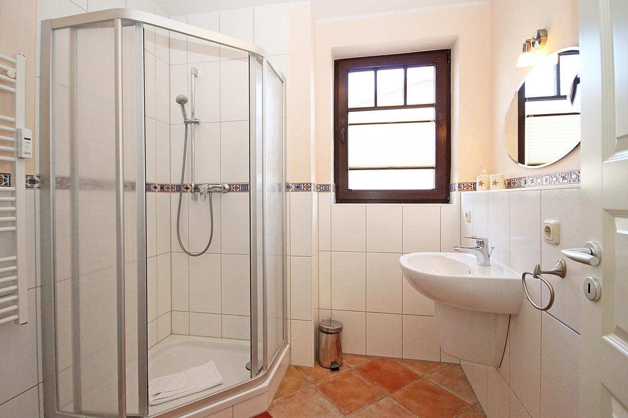 Badezimmer mit Duschkabine, Waschbecken und Fenster.