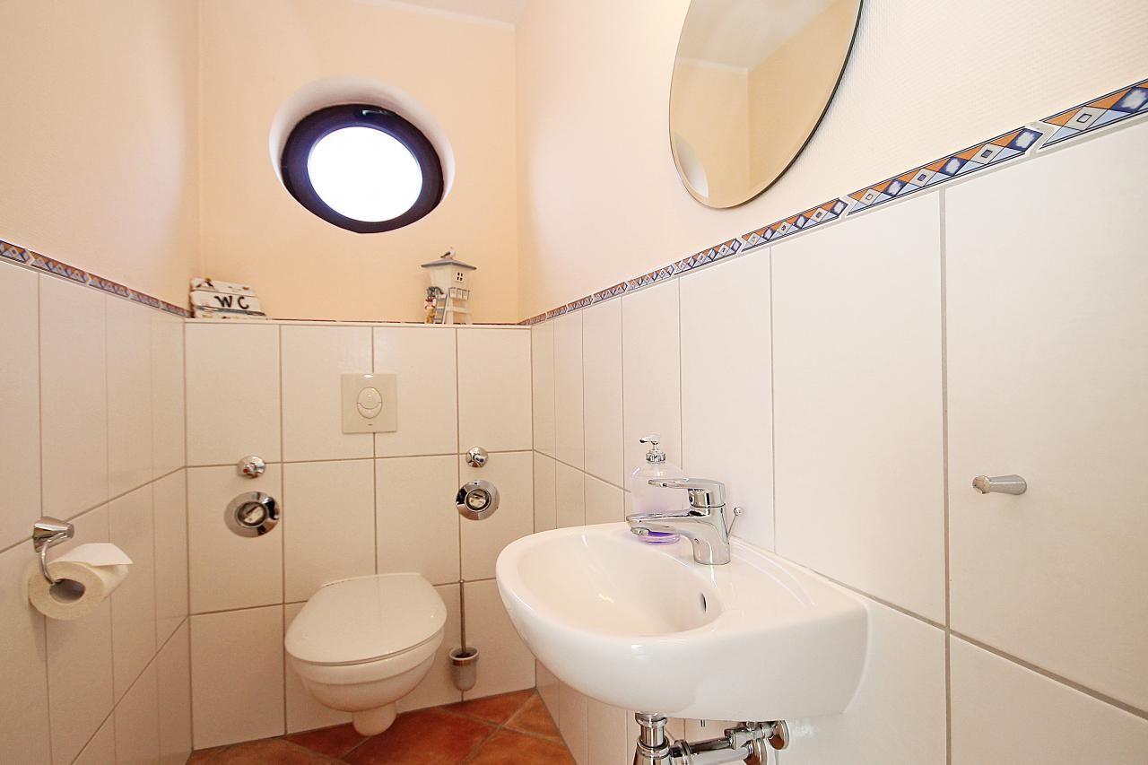Badezimmer mit Toilette, Waschbecken und runden Fenster