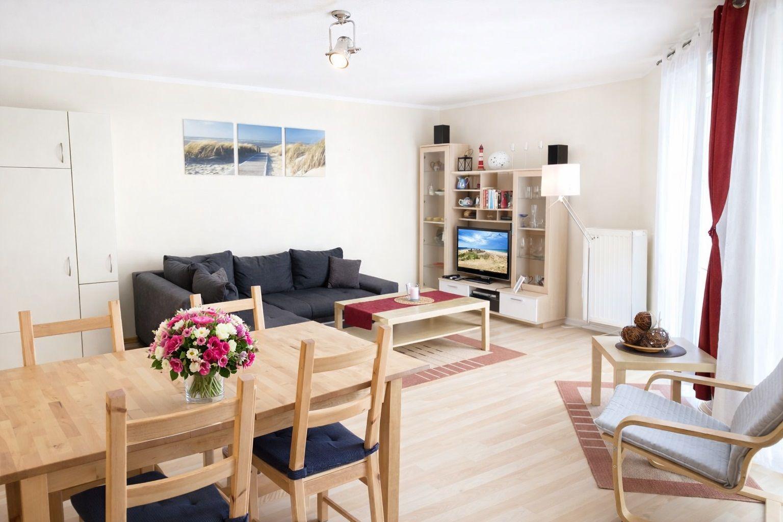 Wohnzimmer mit Essbereich, Sofa, TV und Holzmöbel.