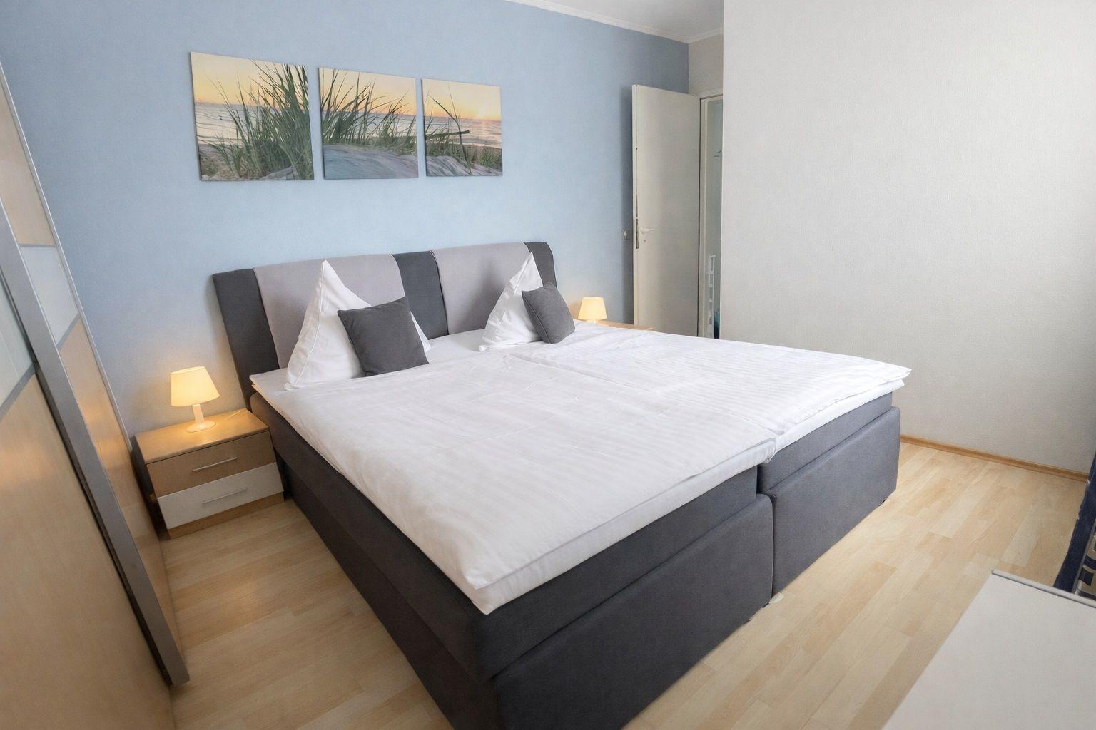Schlafzimmer mit Doppelbett, Nachttisch und Wandbildern.
