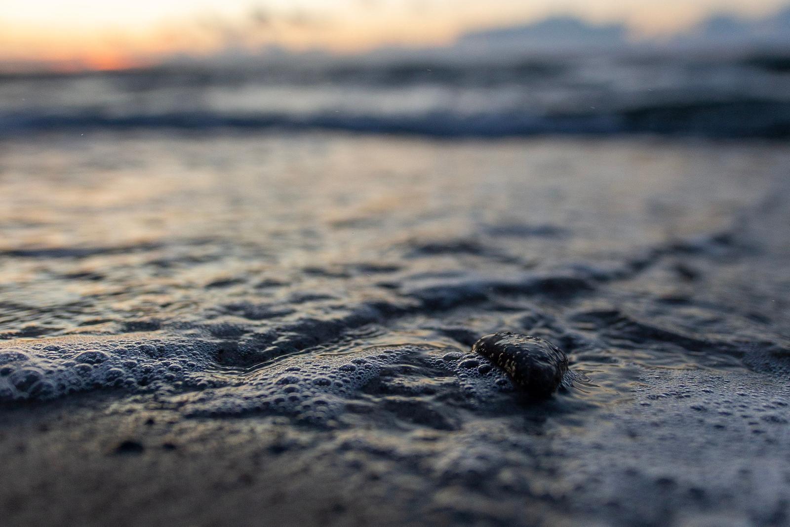 Wellen schlagen sanft auf den Strand bei Sonnenuntergang.