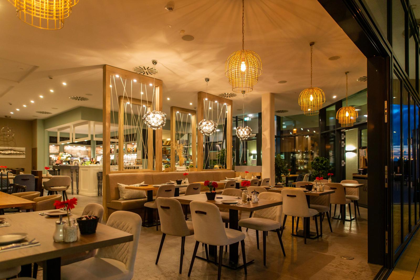 Ein Restaurant mit Tischen, Stühlen und hängenden Lampen.