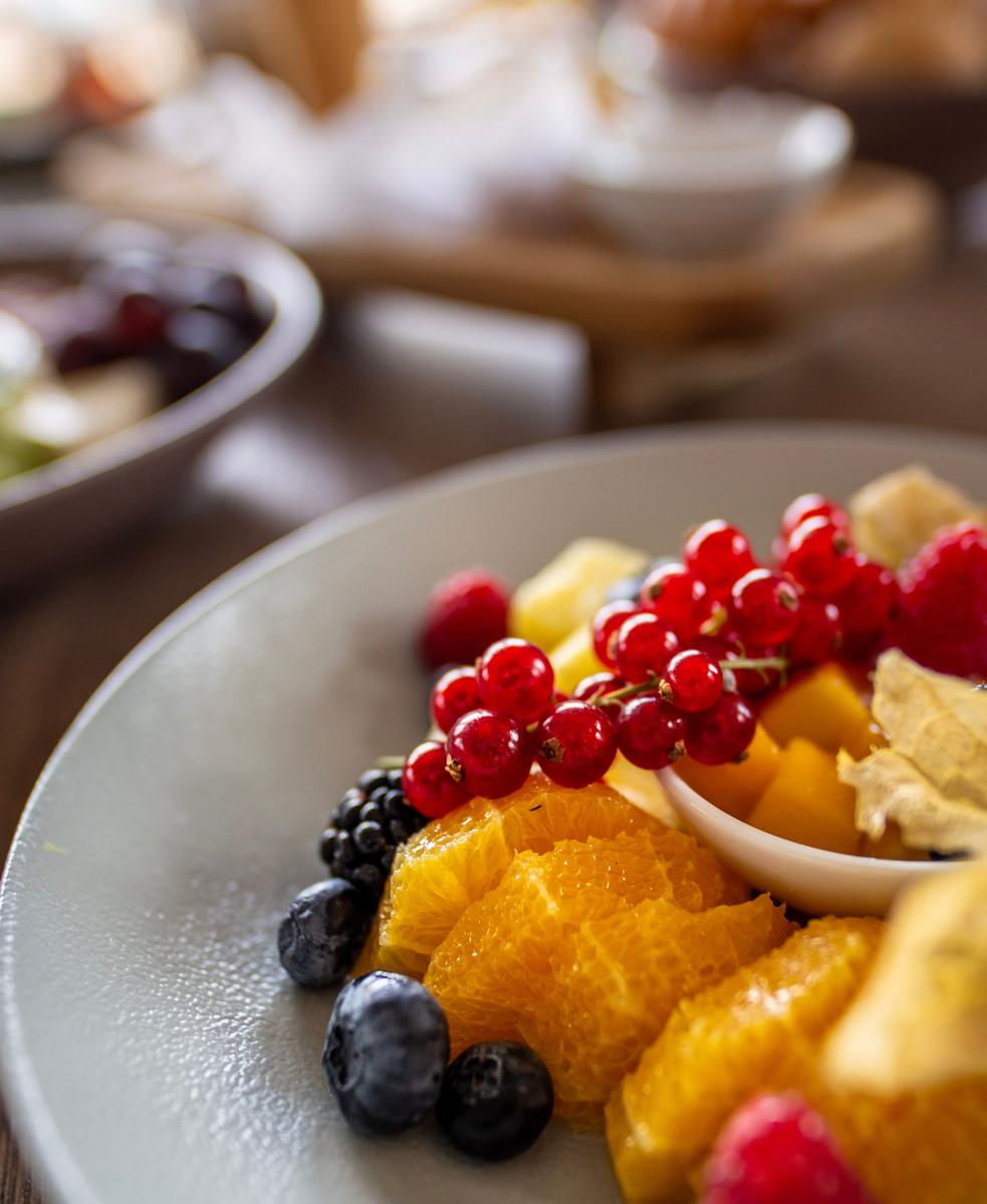Fruchttablett mit Johannisbeeren, Orangen, Himbeeren und Blaubeeren auf Teller