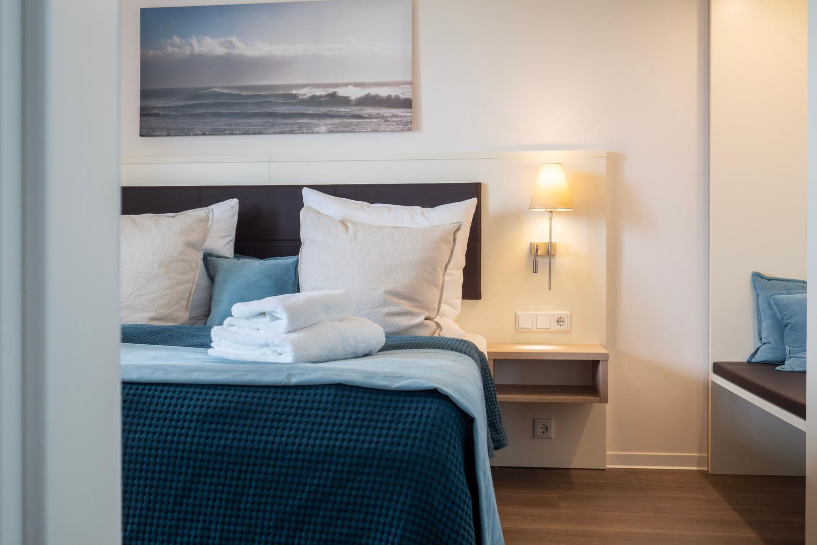 Schlafzimmer mit Bett, Wandlampe und Bild an der Wand.