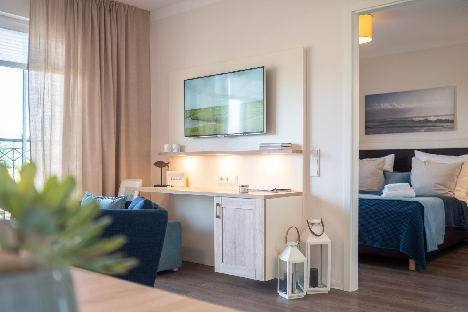 Wohnbereich mit TV und Schlafzimmer im Hintergrund