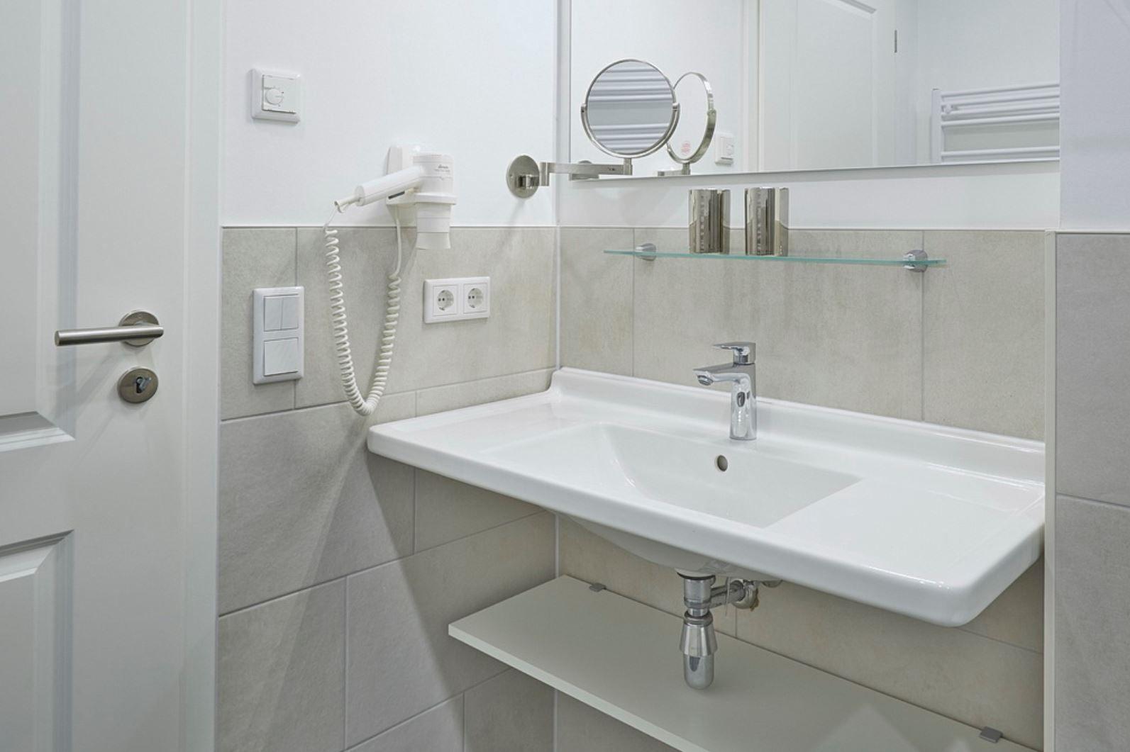 Badezimmer mit Waschbecken, Spiegel und Handtuchhalter