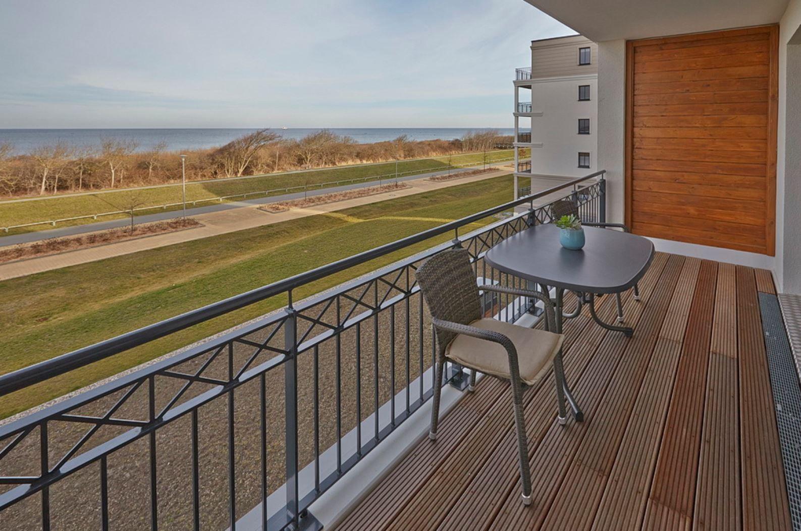 Terrasse mit Tisch und Stühlen, Blick auf Strand und Meer.