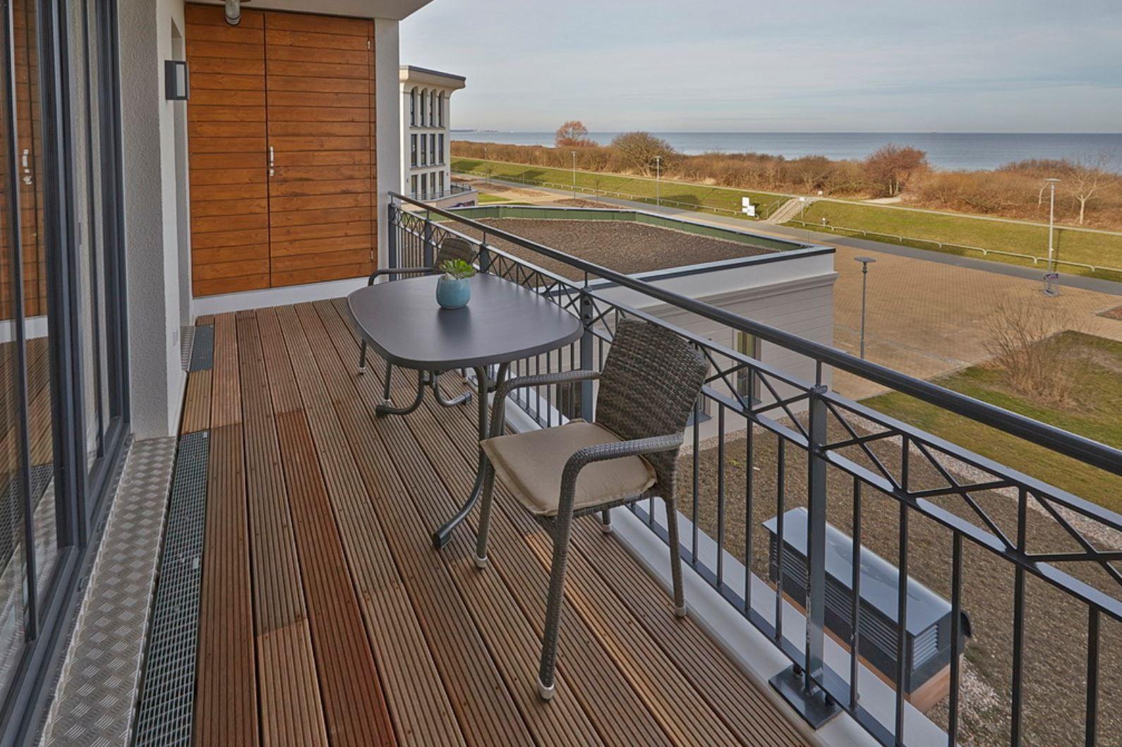Terrasse mit Tisch und Stuhl, Blick auf Meer und Grünfläche