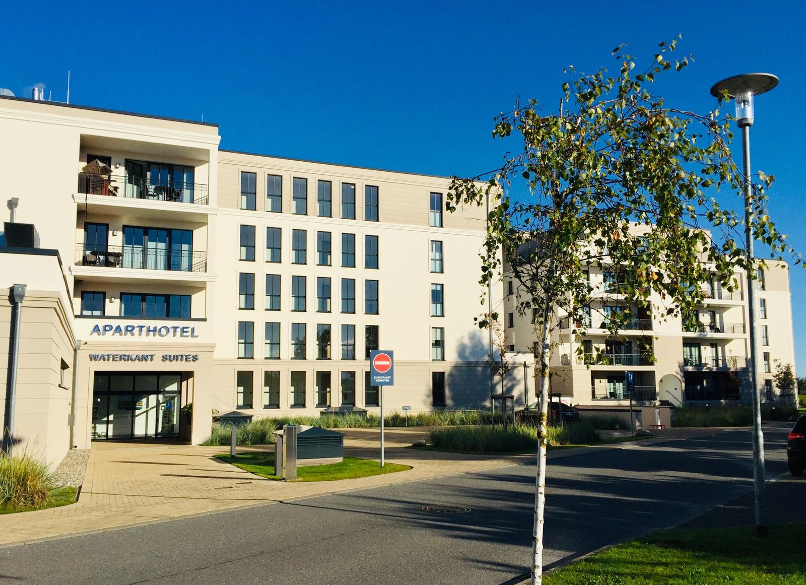 Aparthotel Waterkant Suites mit Balkonen und Glasfassade unter blauem Himmel.