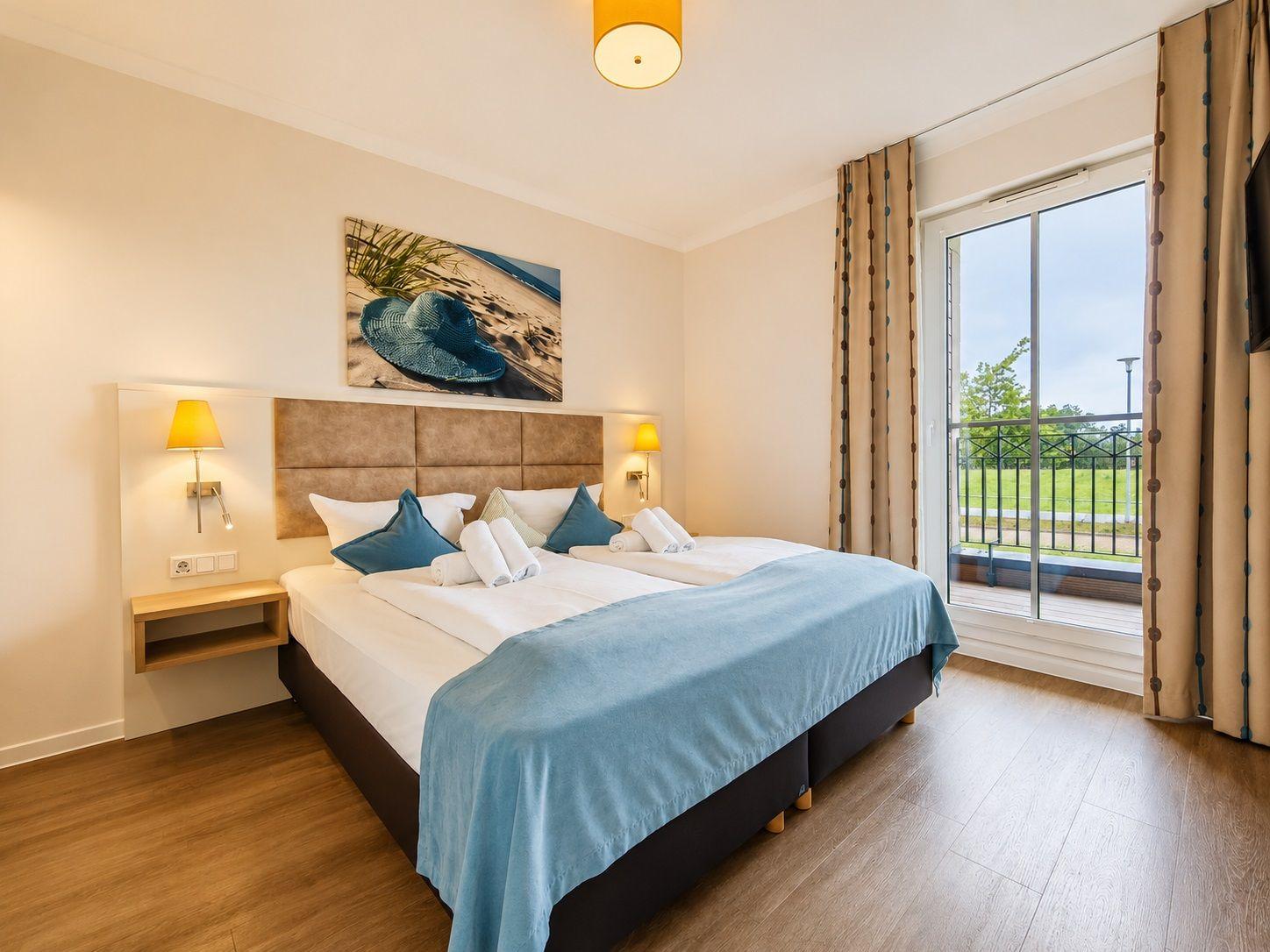 Schlafzimmer mit Doppelbett, Balkon und Wandbild.