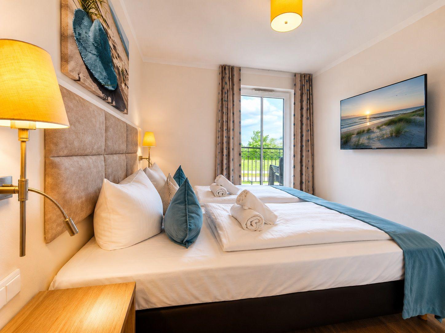 Schlafzimmer mit Doppelbett, Kleiderschrank und Strandbild an der Wand.